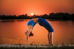 Yoga beim Sonnenuntergang auf das Strand. foto