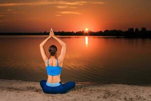 Yoga beim Sonnenuntergang auf das Strand. foto