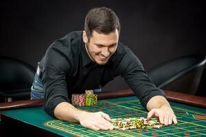 jung gut aussehend Mann spielen Roulette Gewinnt beim das Kasino foto