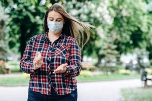Frau plus Größe in einer Schutzmaske, desinfiziert ihre Hände, im Freien