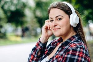 Frau mit Kopfhörern auf dem Hintergrund der Stadt, süßes Lächeln foto