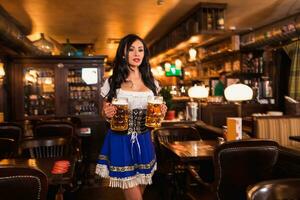 schön weiblich Kellnerin tragen traditionell dirndl und halten enorm Biere im ein Kneipe. foto