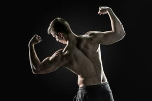 Rückseite Aussicht von muskulös jung Mann zeigen zurück, Bizeps Muskeln foto