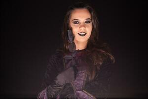 böse und unheimlich weiblich Hexe Über schwarz Hintergrund mit ein Rose. Halloween Kostüm. foto