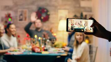 Mädchen nehmen Fotos von ihr Familie mit Smartphone beim Weihnachten Wiedervereinigung. traditionell festlich Weihnachten Abendessen im Mehrgenerationenhaus Familie. genießen Weihnachten Mahlzeit Fest im dekoriert Zimmer. groß Familie Wiedervereinigung