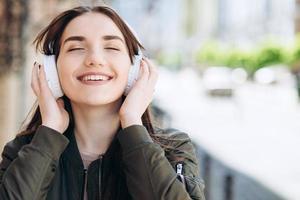 glückliches, junges Mädchen genießt die Musik aus den Kopfhörern. foto