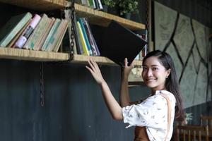 Asiatische Studentinnen, die sich für einen Abschnitt im Bücherregal halten