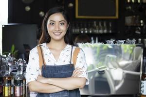 Asiatische Frauen Barista lächelnd und mit Kaffeemaschine in der Cafétheke - berufstätige Frau Kleinunternehmerin Essen und Trinken Café-Konzept