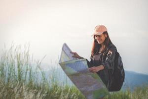 Asiatische junge Frauen, die mit Freunden wandern, Rucksäcke, die zusammen spazieren gehen und eine Karte suchen und eine Fotokamera an der Straße machen und glücklich aussehen, entspannen Sie sich bei Urlaubskonzeptreisen foto