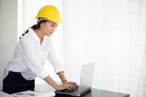 Asiatische Frauen, die Ingenieurinspektion und -Arbeiten und Blaupausen im Büro halten foto