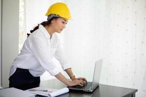 Asiatische Frauen, die Ingenieurinspektion und -Arbeiten und Blaupausen im Büro halten foto