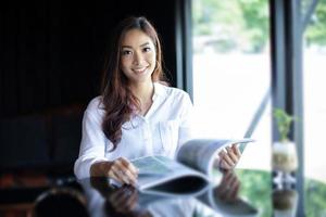 asiatische Frauen lächeln und lesen ein Buch zur Entspannung im Kaffeecafé foto