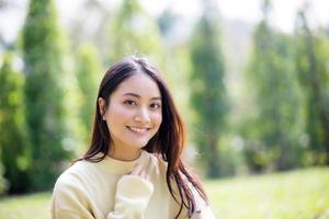 schöne asiatische Frau, die glückliches Mädchen lächelt und warme Kleidung trägt Winter- und Herbstporträt im Freien im Park
