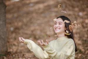 schöne asiatische Frau, die glückliches Mädchen lächelt und warme Kleidung trägt Winter- und Herbstporträt im Freien im Park foto