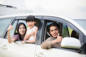 glückliches kleines Mädchen mit asiatischer Familie, die im Auto sitzt, um Roadtrip und Sommerurlaub im Wohnmobil zu genießen? foto