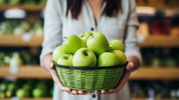 ai generiert ein Frau halten ein Grün Apfel mit ein beißen genommen aus von Es, mit ein Korb von Äpfel im das Hintergrund foto