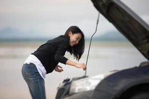 Asiatische Frau mit Handy beim Suchen und gestresster Mann, der nach einer Autopanne auf der Straße sitzt foto