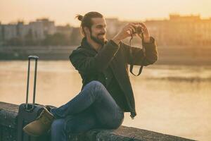 gut aussehend modern Geschäftsmann mit Koffer genießt Fotografieren Stadt.getönt Bild foto