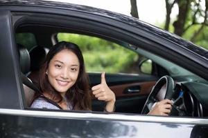 schöne asiatische Frau, die lächelt und genießt. Autofahren auf der Straße für Reisen foto