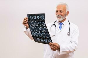 Porträt von Senior Arzt Arzt halten x Strahl Bild auf grau Hintergrund. foto