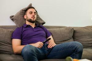 Mann fiel schlafend während Aufpassen Fernseher während Sitzung auf Sofa im seine Leben Zimmer. foto