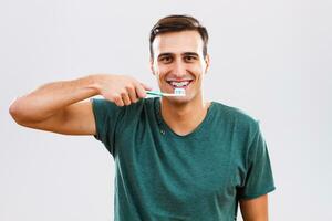 Mann mit Hosenträger Bürsten seine Zähne foto