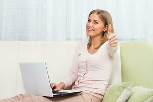 Frau mit Laptop und zeigen Daumen hoch. foto