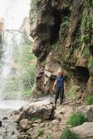 Frau, die am schönen Bergwasserfall vorbeigeht foto