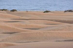 ein groß Sand Düne mit ein Zaun im das Mitte foto