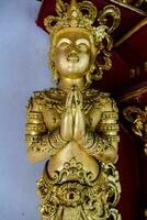 ein Gold Statue von ein Buddha mit Hände gefaltet foto