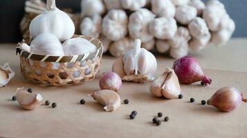 organisch roh Knoblauch Birne im Bambus Korb auf ein hölzern Tabelle und Knoblauch Nelken, Zwiebeln, schwarz Pfefferkörner von Essen Zutaten foto