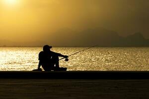 Silhouette von Mann Angeln auf ein See. foto