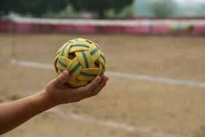 Nahansicht Mann halt sepak takraw Ball draussen. Konzept, asiatisch traditionell Sport. ein Ball gemacht von Rattan oder Synthetik Plastik. Sport mit Ausrüstung Das können abspielen zum draussen oder drinnen. wettbewerbsfähig Spiel. foto