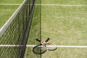 ein Tennisschläger und ein neuer Tennisball auf einem frisch gestrichenen Tennisplatz foto