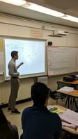 ai generiert ein Lehrer Stehen im Vorderseite von ein Whiteboard erklären ein Konzept zu ein Klassenzimmer voll von Studenten foto