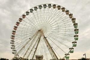 ein groß Ferris Rad ist gezeigt im Vorderseite von ein wolkig Himmel foto