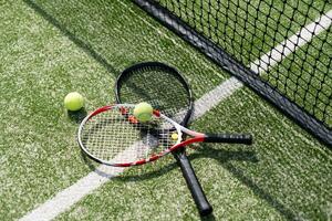 ein Tennisschläger und ein neuer Tennisball auf einem frisch gestrichenen Tennisplatz foto