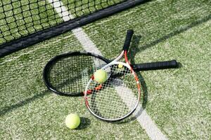 ein Tennisschläger und ein neuer Tennisball auf einem frisch gestrichenen Tennisplatz foto