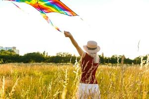 Schönheit Mädchen Laufen mit Drachen auf das Feld. schön jung Frau mit fliegend bunt Drachen Über klar Blau Himmel. frei, Freiheit Konzept. Emotionen, gesund Lebensstil foto