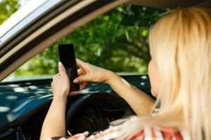 jung weiblich Treiber mit berühren Bildschirm Smartphone und Geographisches Positionierungs System Navigation im ein Wagen. foto