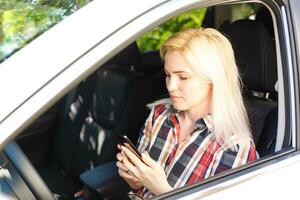 jung weiblich Treiber mit berühren Bildschirm Smartphone und Geographisches Positionierungs System Navigation im ein Wagen. foto