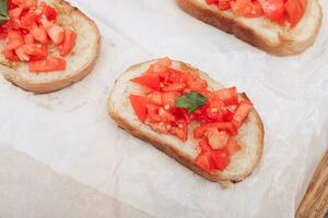 köstlich Bruschetta, getoastet Brot mit Tomaten auf Weiß Papier foto