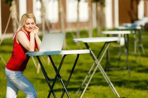 jung ziemlich Frau mit Laptop auf das Bank im ein Park foto