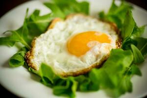 einer gebraten Ei mit Rucola und Grüner Salat im ein Teller foto