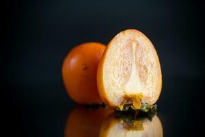 reif Schnitt Hälfte Persimmon isoliert auf schwarz foto