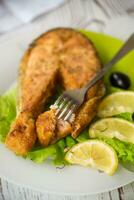 Stück von gebraten Lachs Fisch im ein Teller mit Zitrone foto