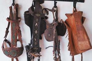 Pferdezaumzeug und Gebisse aus Leder an der Wand hängen foto