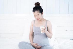 asiatische schwangere frau, die ein glas milch hält foto