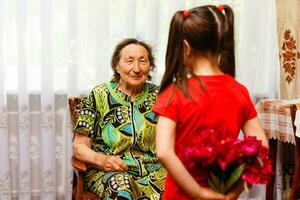 wenig Mädchen Besuch ihr krank Oma geben Blumen foto