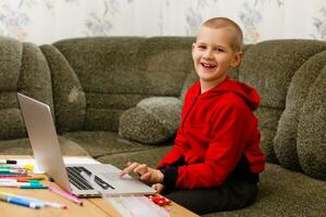 glücklich Junge Sitzung beim seine Schreibtisch mit Laptop Computer foto